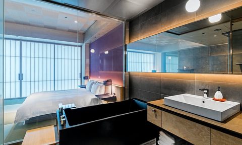 Interior of a hotel room with a bed, bathtub, and sink in one room