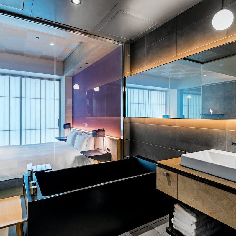 Interior of a hotel room with a bed, bathtub, and sink in one room