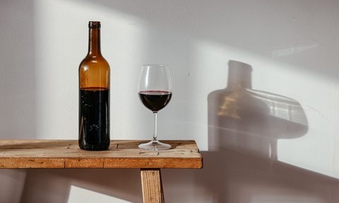 Bottle and glass of red wine on a bench