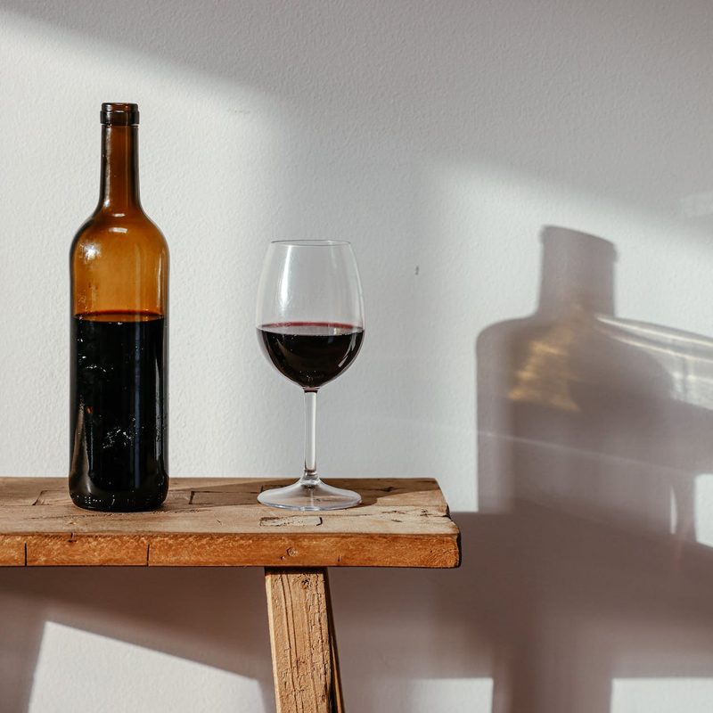 Bottle and glass of red wine on a bench