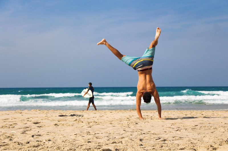 Man doing a handstand on a sandy beach