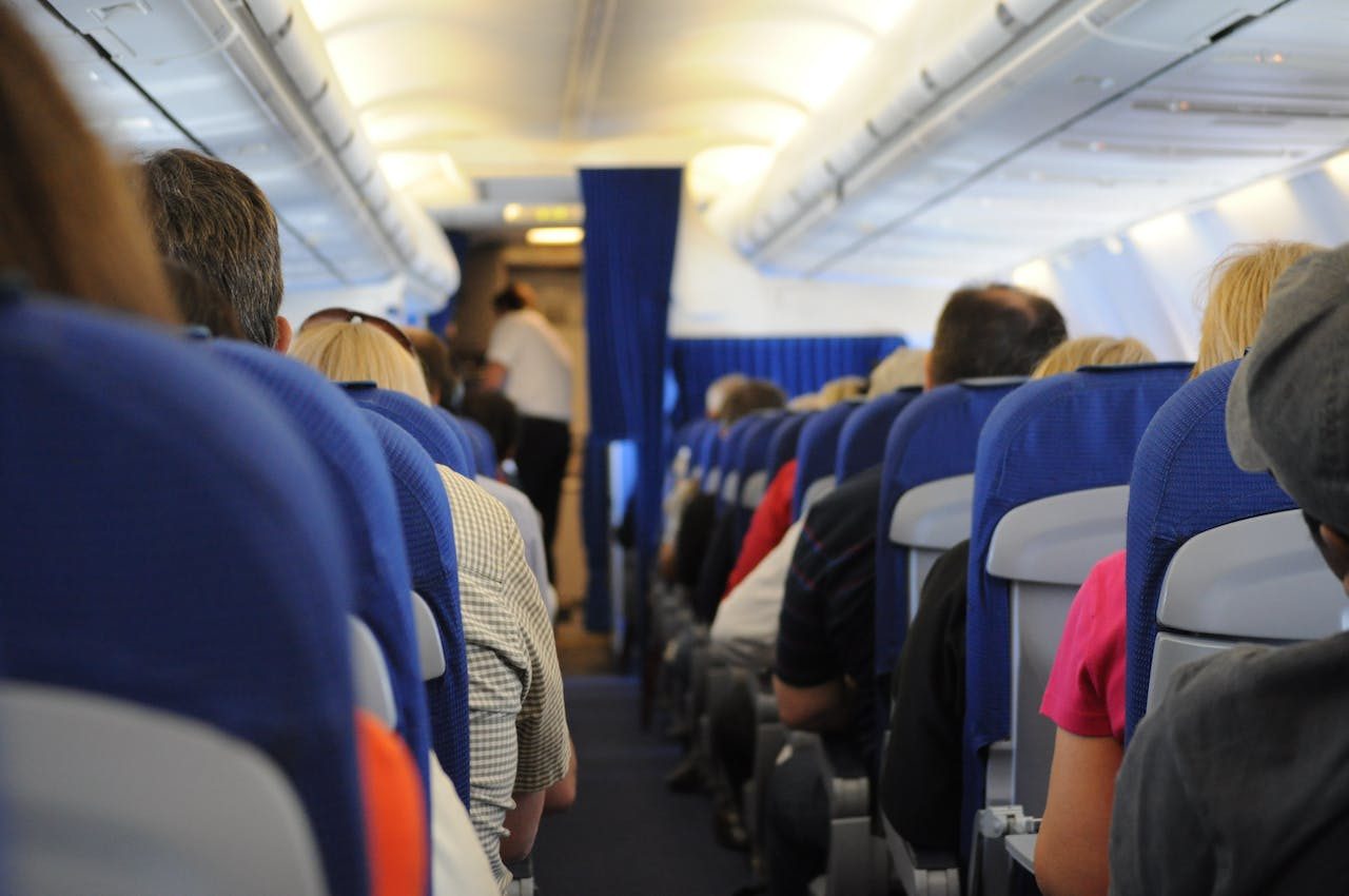 The interior of an airplane, showing the backs of seats with passengers seated