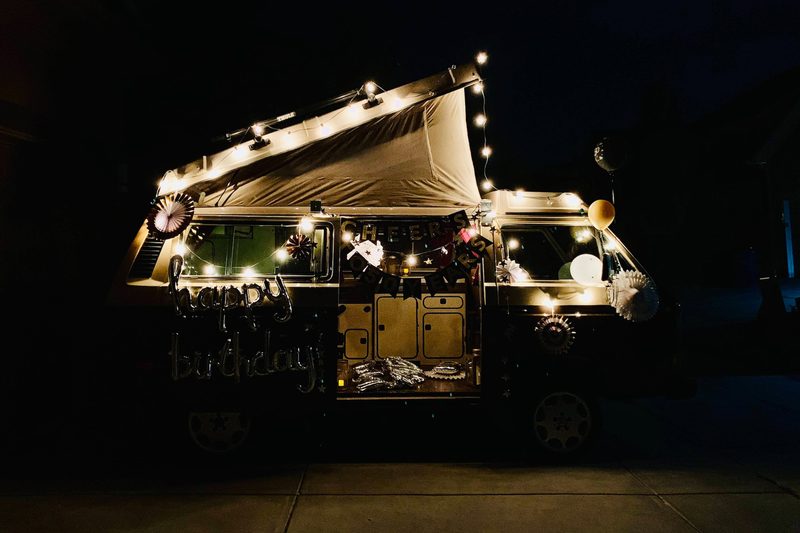 Vintage pop-up camper van decked out with string lights at night.