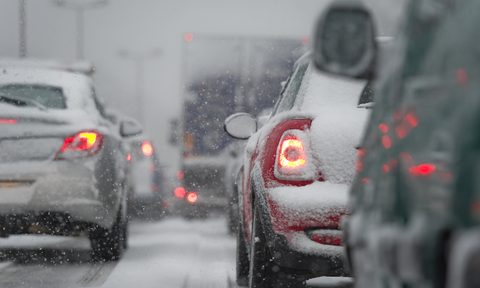 Cars stopped on a freeway during a snowstorm.