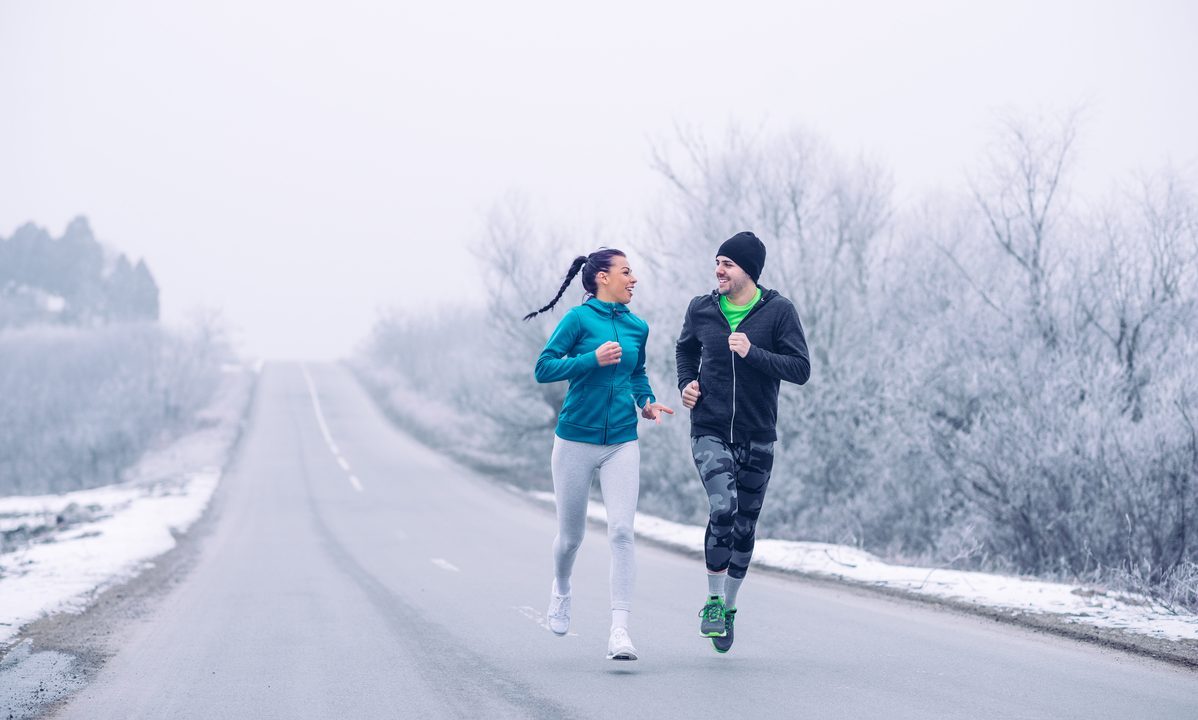 A man and woman running on a snowy winter road