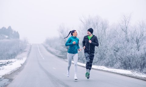A man and woman running on a snowy winter road