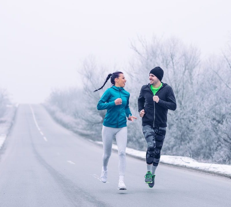 A man and woman running on a snowy winter road