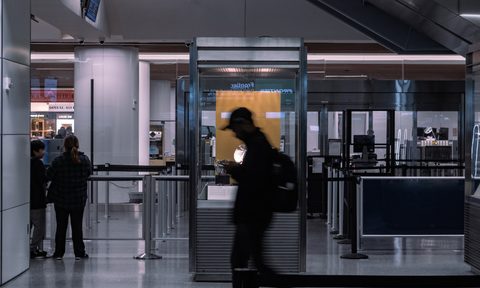 A man walking past an airport security station in motion