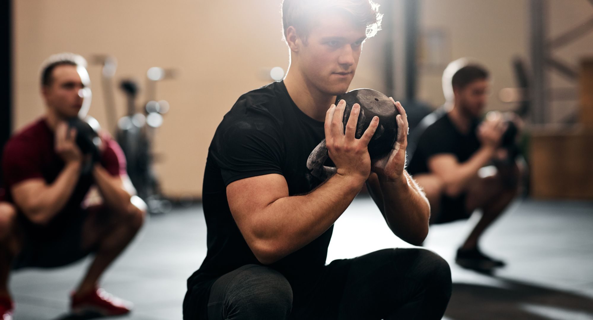 Young males doing squats with weights at the gym