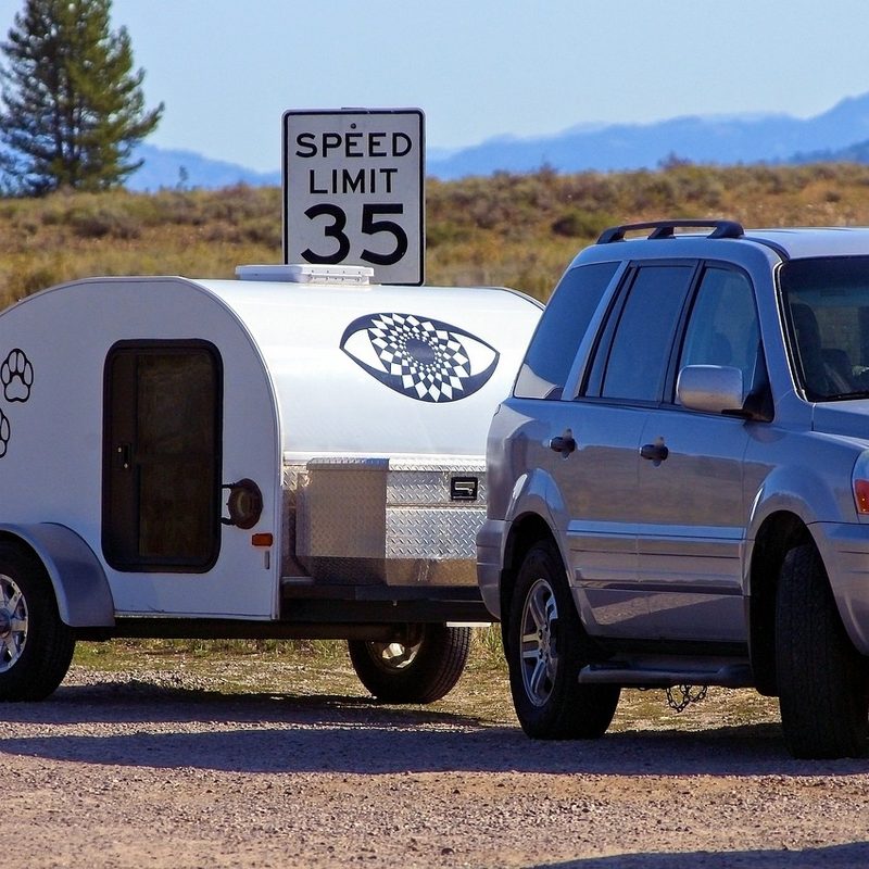An SUV pulling a teardrop trailer in nature