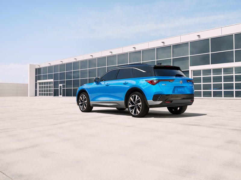 2024 Acura ZDX Type S blue body with a black roof left rear three-quarter view with a glass-sided building in the background.