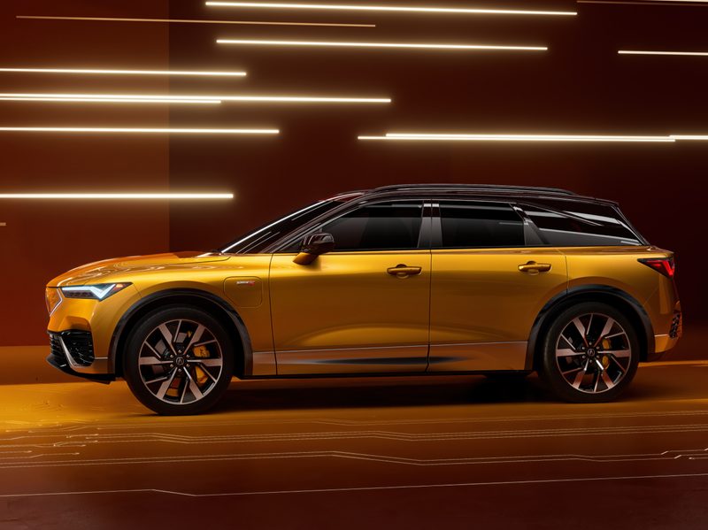 2024 Acura ZDX Type S in a bright gold color with a black top against a red background.
