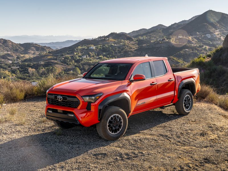 2024 Toyota Tacoma i-Force Max hybrid pickup parked on a hill with mountains and desert in the background