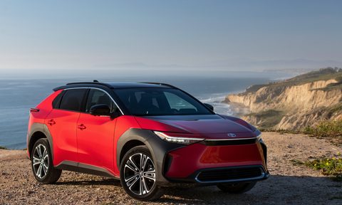 2024 Toyota bZ4X Limited AWD SupersonicRed parked on a cliff top with ocean below.