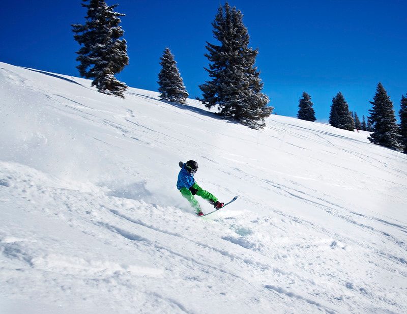 Snowboarder doing a tail butter through deep powder at Vail Resort