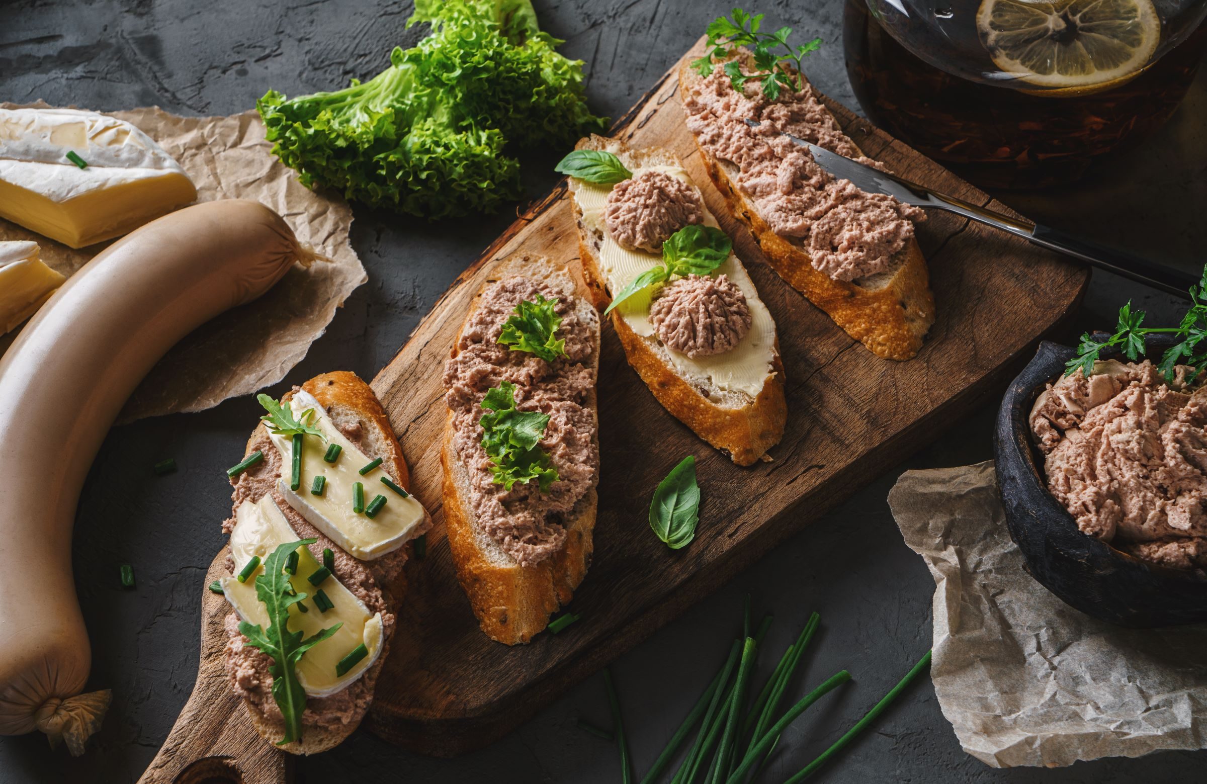 Liver pate with herbs and cheese and green onion on french bread on table