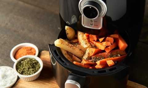 Cooking potatoes and carrot sticks with spices in an air fryer