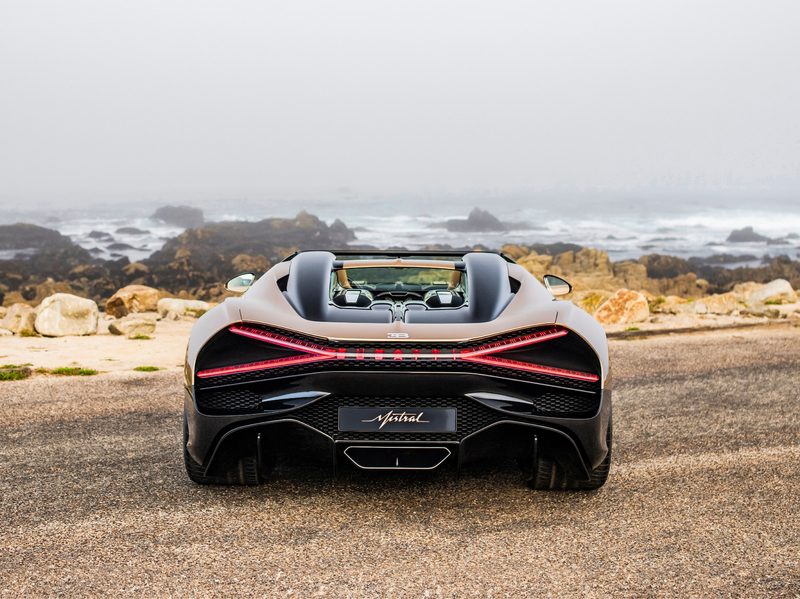 Bugatti W16 Mistral Roadster parked on pavement rear view of the car overlooked a rocky ocean coast.