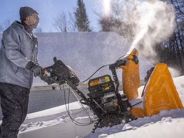 A man using a Cub Cadet 3X 26-inch snow blower on an incline.