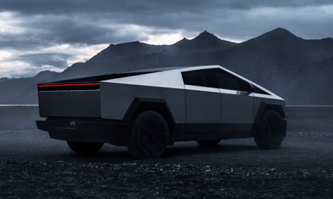 Tesla Cybertruck parked outside with a mountain in the background.