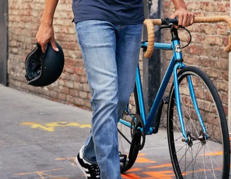 Man in Duer jeans walking a bike