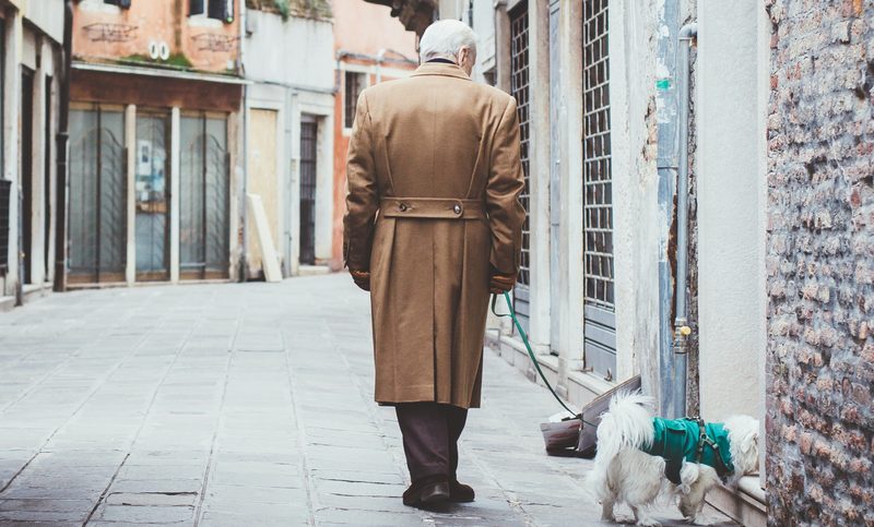 Man in trench coat walking a dog