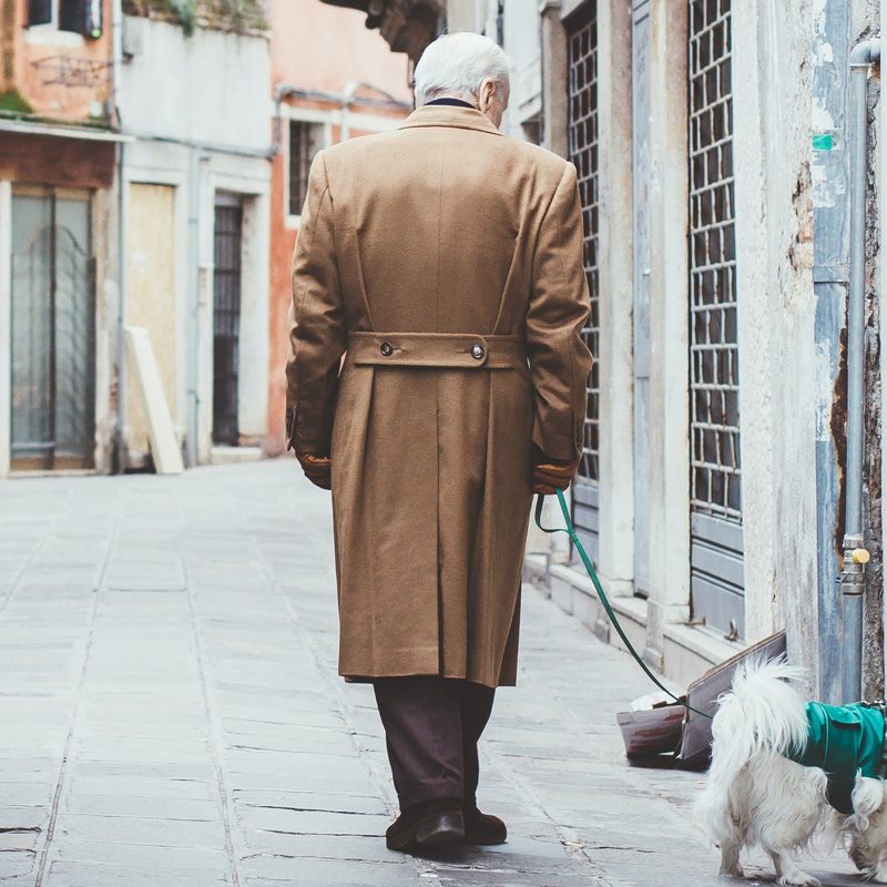Man in trench coat walking a dog