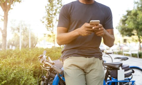 Man leaning on a bike in chinos