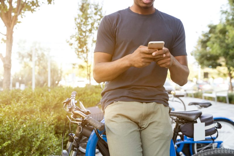 Man leaning on a bike in chinos