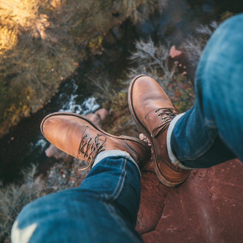 Man on cliff in leather boots