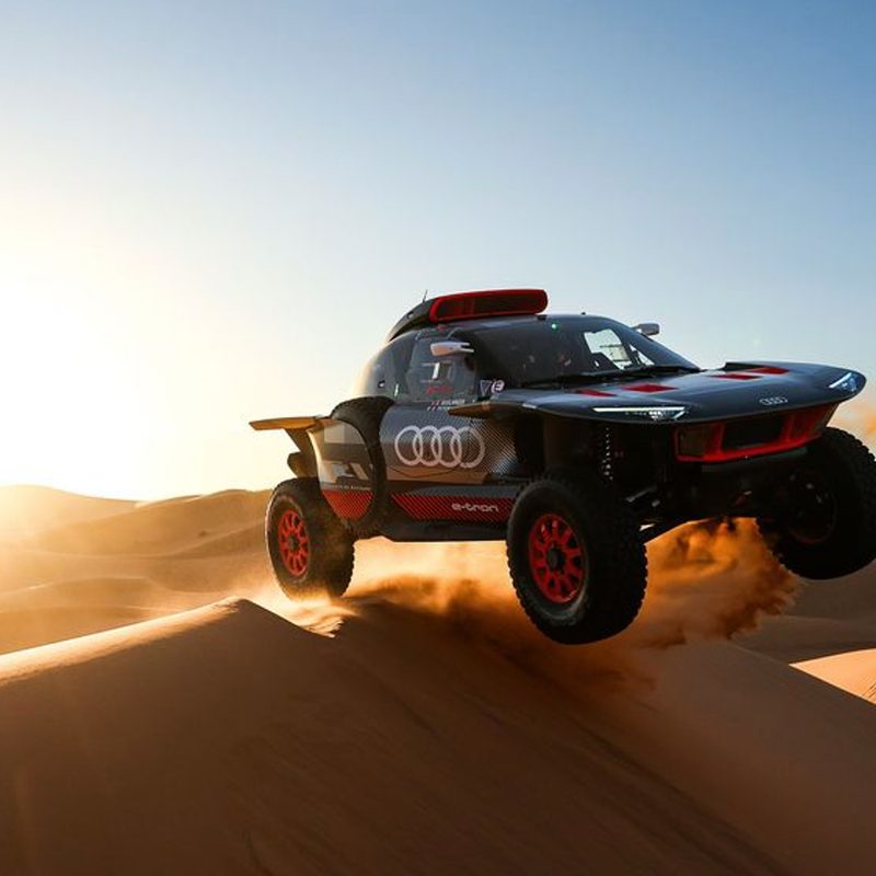 Non-production Audi RS Q e-tron racing across desert dunes.