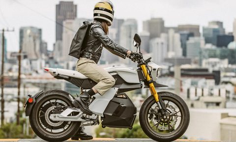 Rider on a Ryvid Anthem electric motorcycle stopped on a street, overlooking a city.