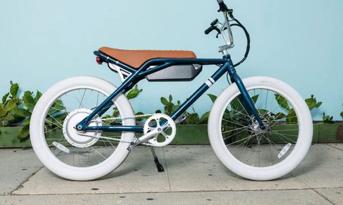Sole e-24 e-bike in the Whaler colorway parked on a sidewalk with a light blue background.