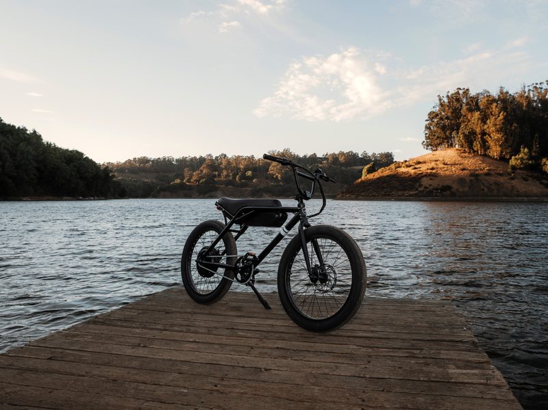 Sole e-24 electric bike on a dock on a lake with the setting sun on a hillside in the background.