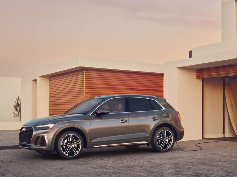 Taupe 2024 Audi Q5 PHEV with a charger cable extending from a garage.