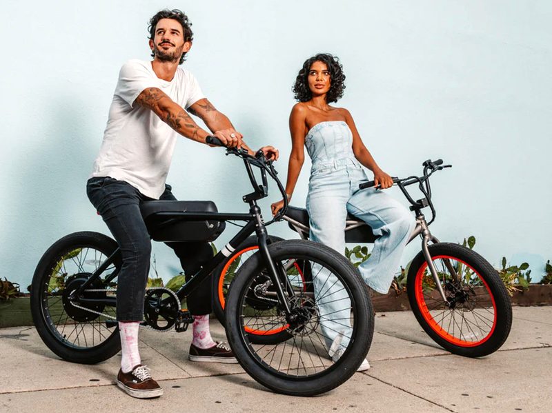 Two people sitting on Sole e-24 e-bikes with Overthrow and el Tigre colorways.