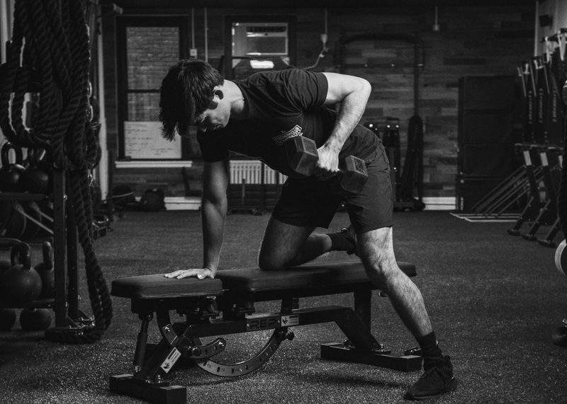 Man doing dumbbell rows on bench black and white pic
