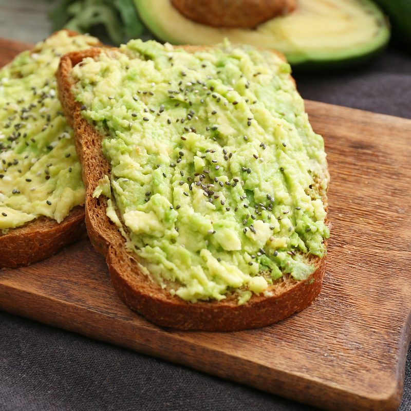 Tasty avocado toasts on wooden board