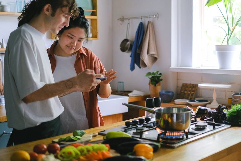 a couple cooking in the kitchen looking at phone