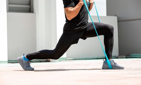 man doing lunge exercise with resistance band indoors