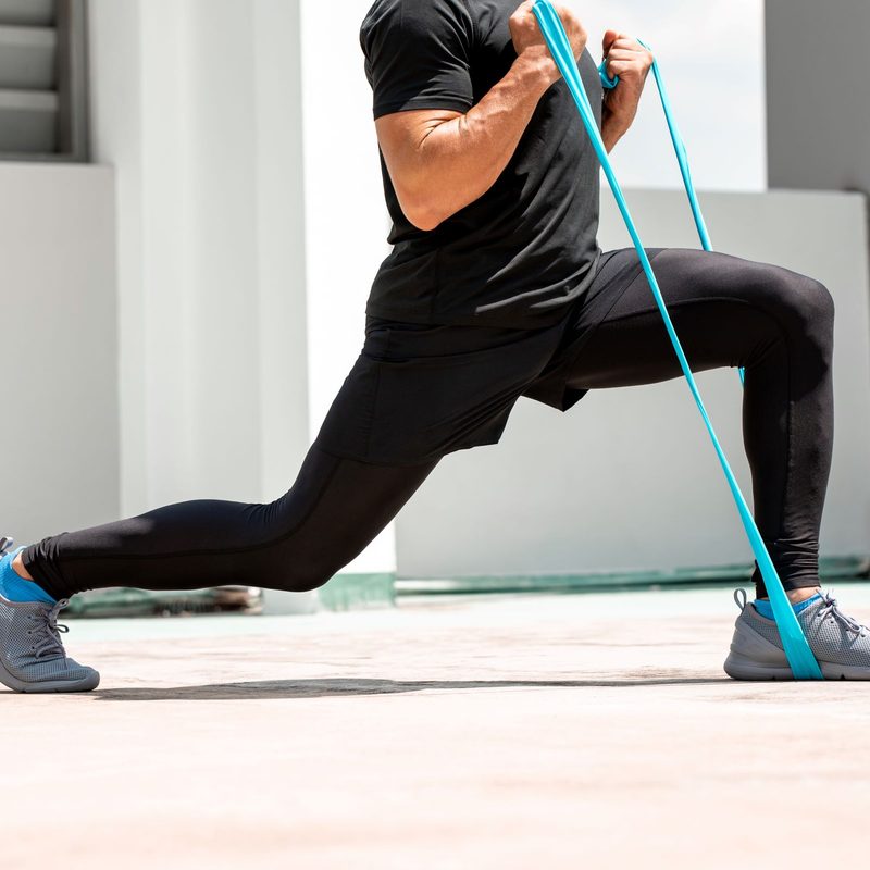 man doing lunge exercise with resistance band indoors
