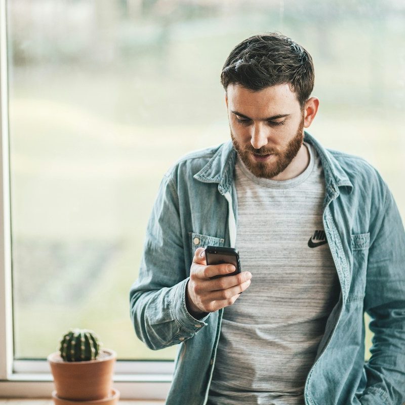 A man looking at his phone in an airy room
