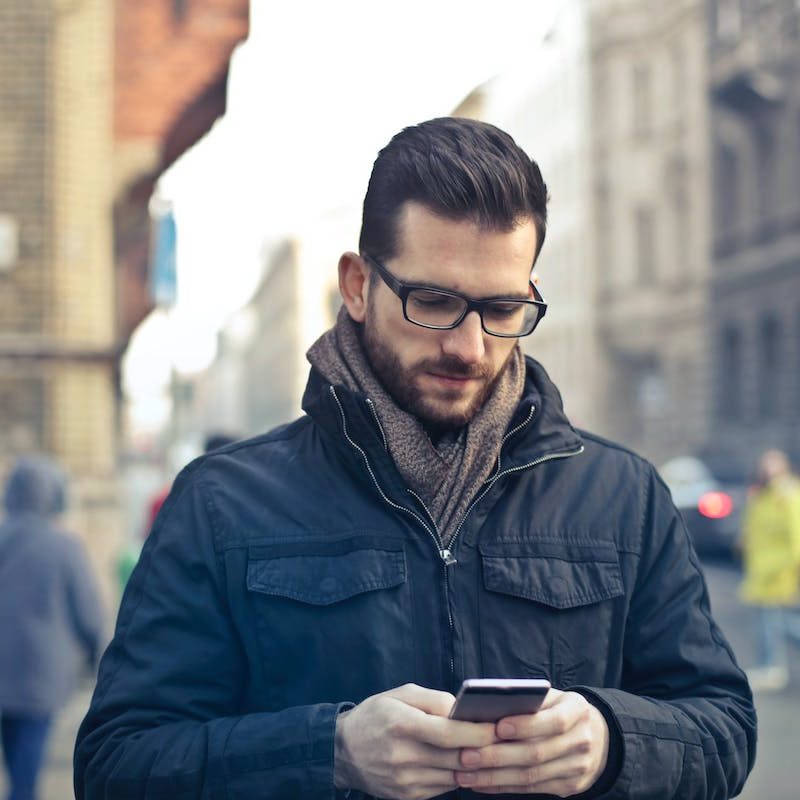 man looking at phone in city during winter