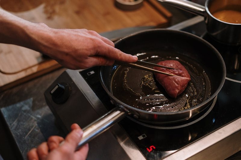 Person cooking a steak in a pan