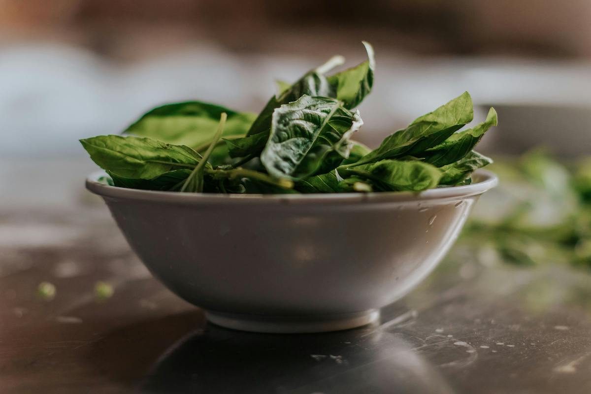 a bowl of spinach on a wood table