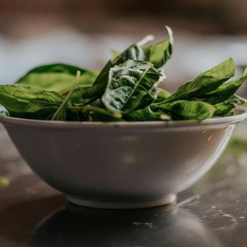 A bowl of spinach on a wood table