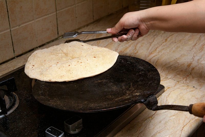 Person warming tortilla on stovetop