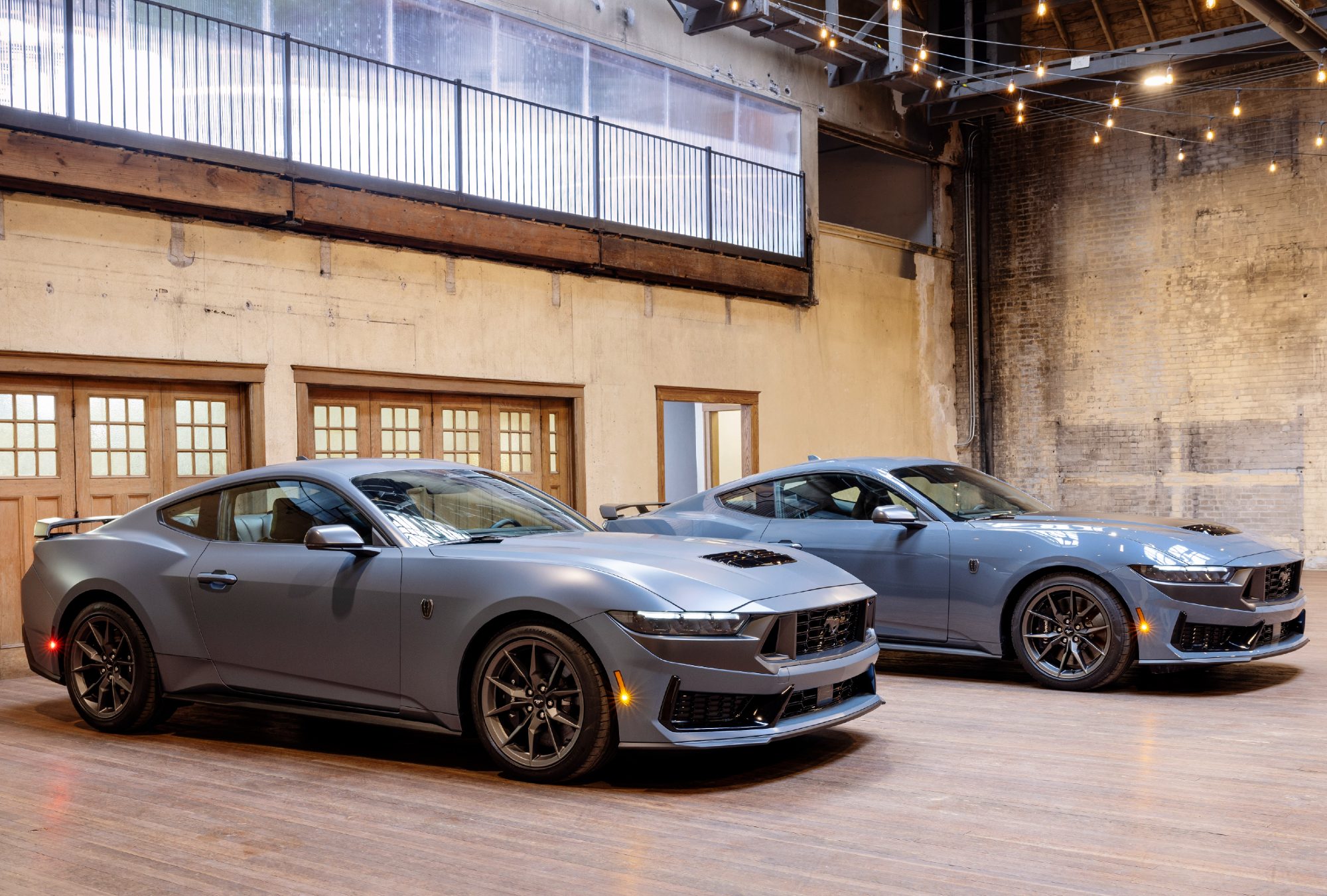 2024 Ford Mustangs with and without Matte Clear Film right front three-quarter view with the cars in an empty brick-wall warehouse.