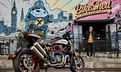 2024 Indian FTR x RSD Super Hooligan parked in front of Bike Shed store with a person leaning against metal fence looking directly at the camera.