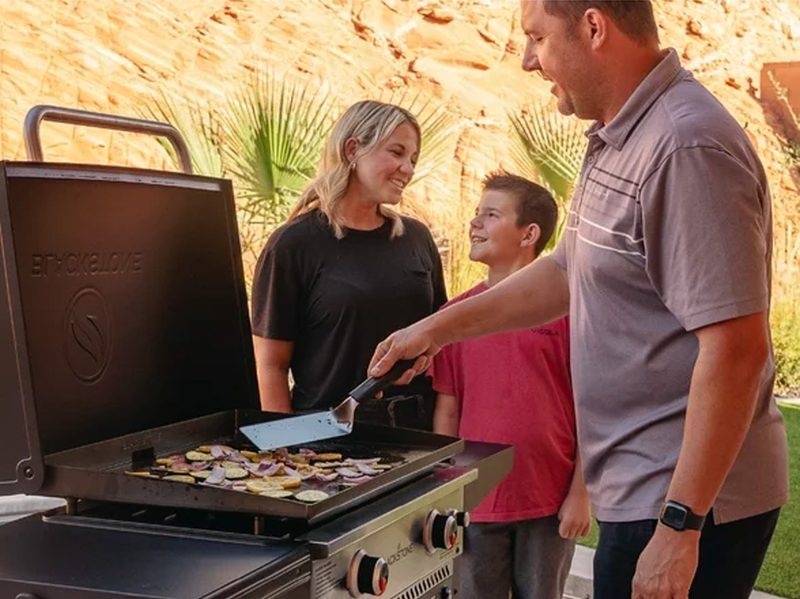 A family cooks on the Blackstone 28-inch propane griddle with air fryer.